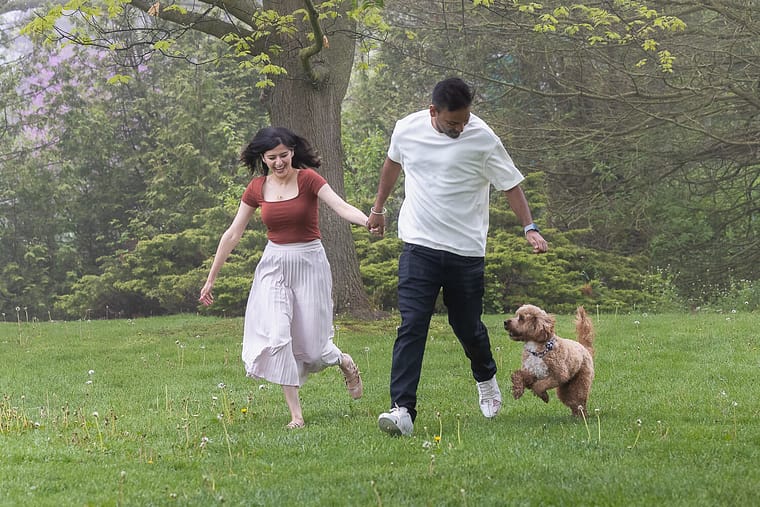 a candid moment of dog pet parents running with their dog in a dog photo shoot in Oakville